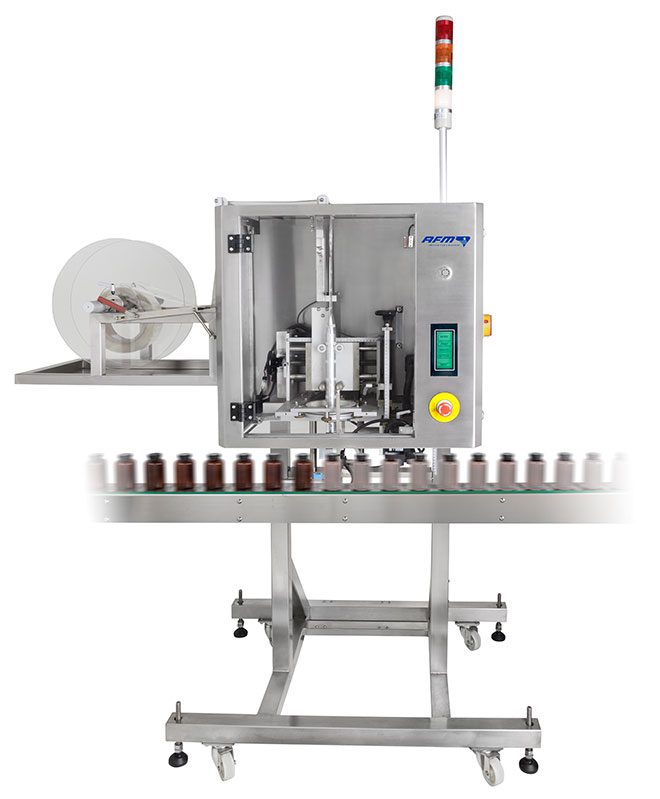Automated labeling machine applying labels to small bottles on a conveyor belt.